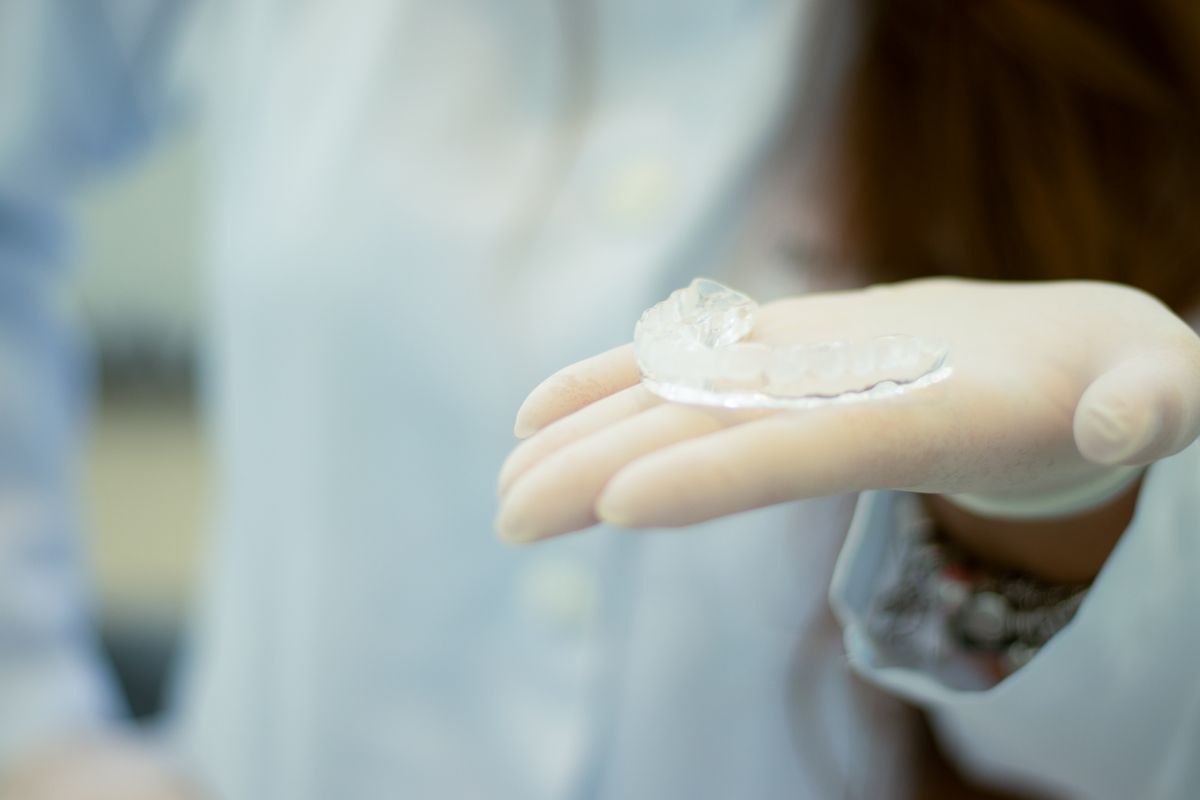 Custom clear dental night guard held by gloved hand